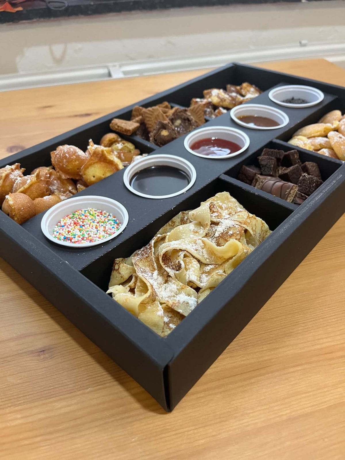Boîte découverte Ranieri : pâtisseries et gourmandises en compartiments, coulis et vermicelles servis à part. Vue 2, exemple de présentation.