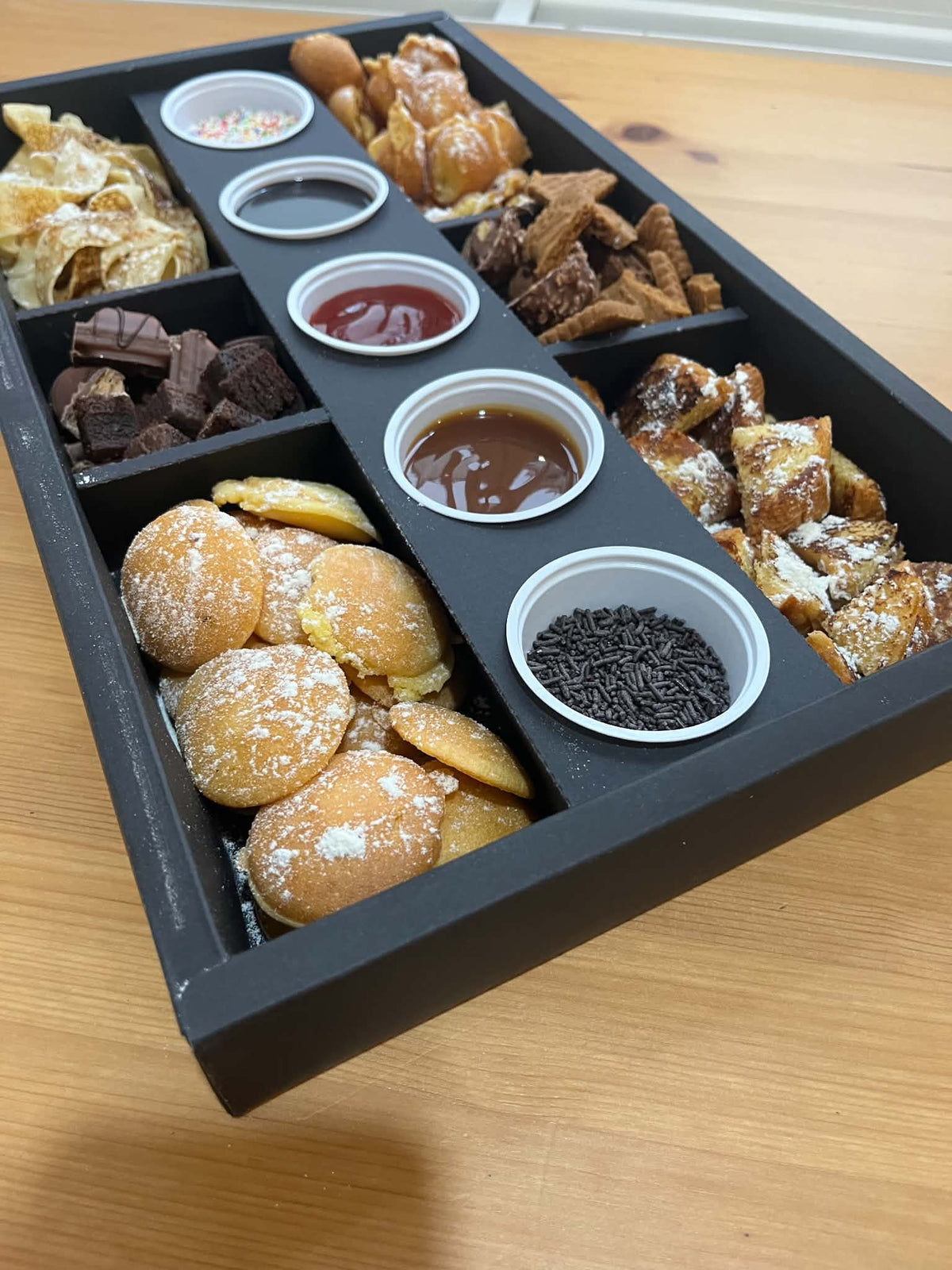 Boîte découverte Ranieri : pâtisseries et gourmandises en compartiments, coulis et vermicelles servis à part. Vue 3, exemple de présentation.