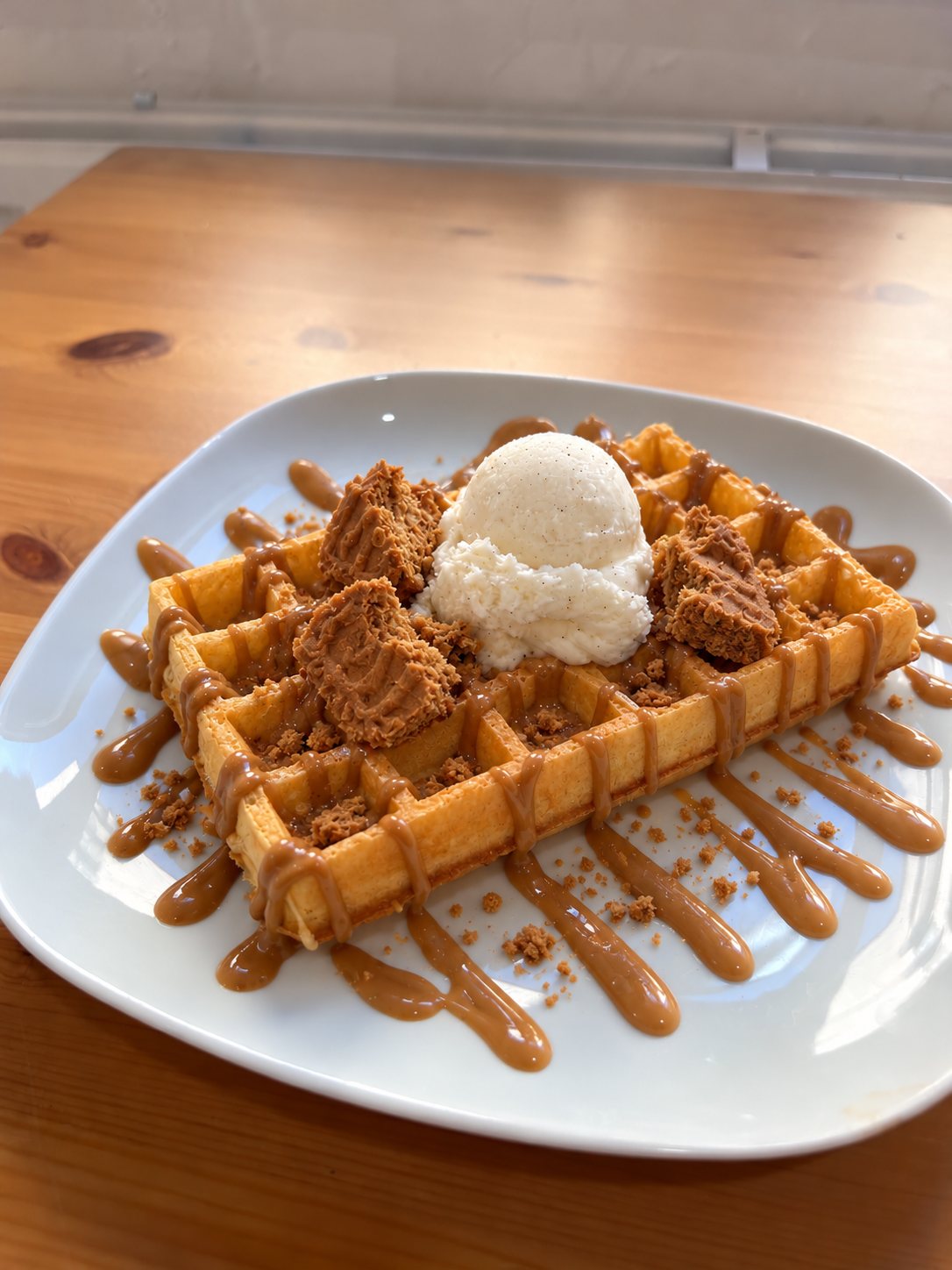 Gaufre de Bruxelles spéculoos avec morceaux de spéculoos, coulis spéculoos, une boule de glace vanille et chantilly. Suggestion de présentation ; accompagnements servis à part.